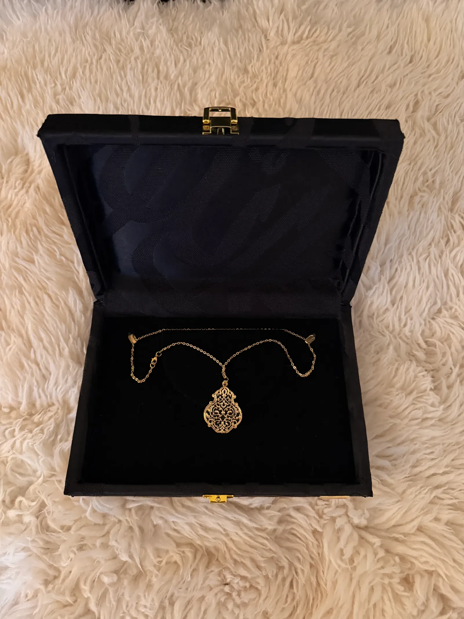 Feine goldfarbene Kette mit Filigran-Tropfenanhänger in geöffneter schwarzer Präsentationsbox